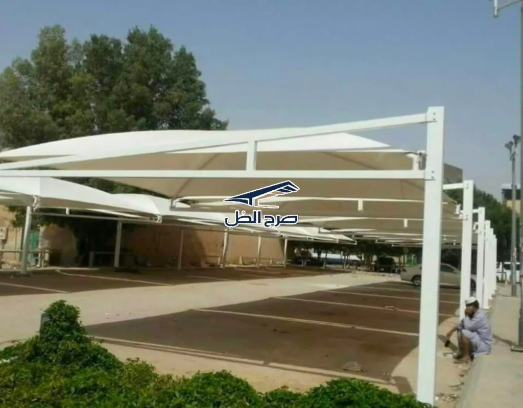 مظلة بيضاء فوق موقف خارجي بجوار مساحة خضراء