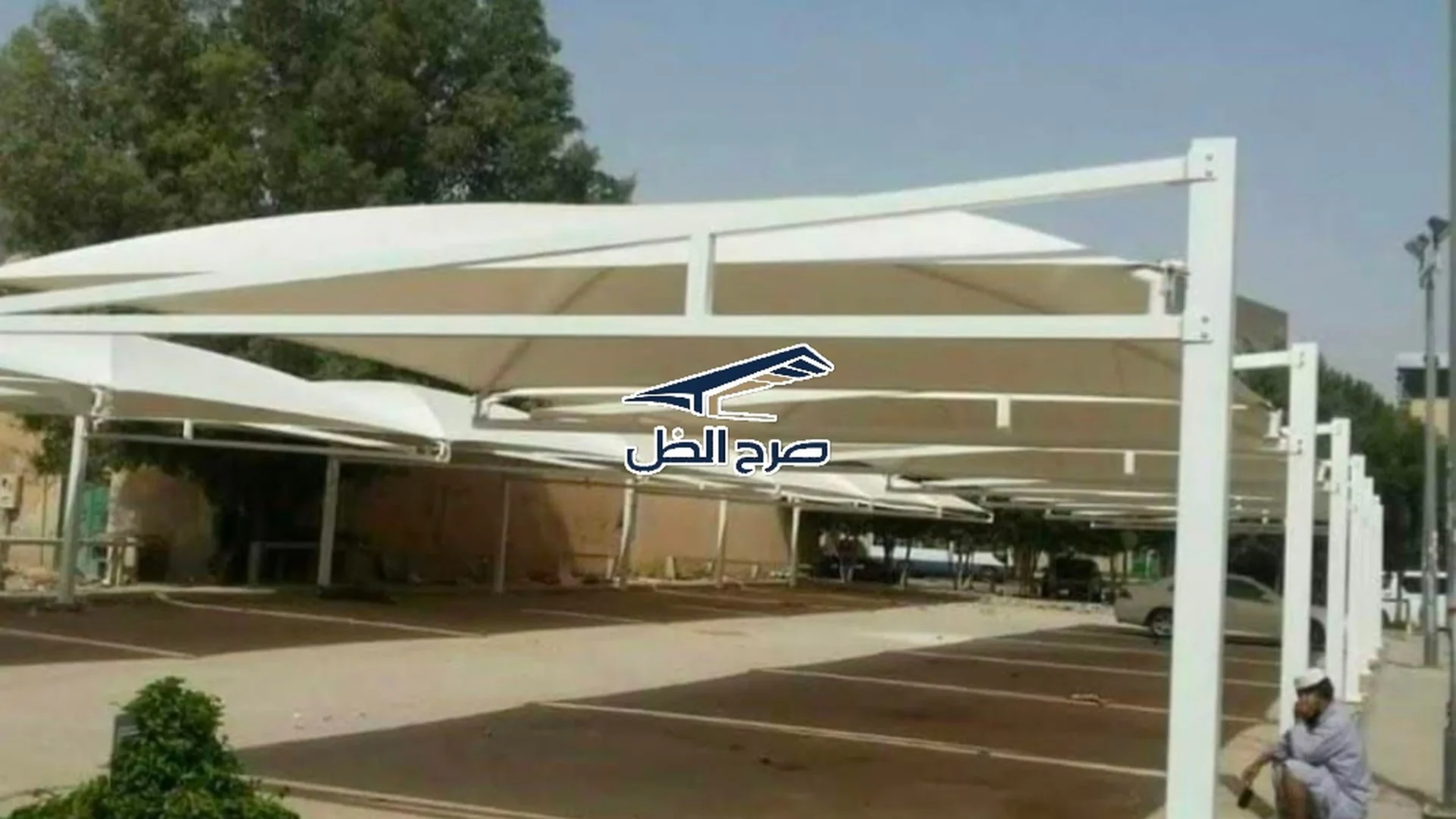 مظلة بيضاء فوق موقف خارجي بجوار مساحة خضراء