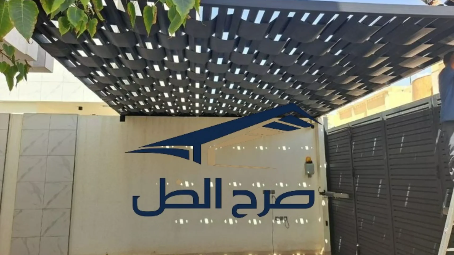 برجولة شرائح داكنة فوق فناء منزلي محاط بالنباتات