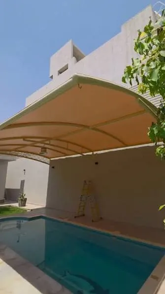 مظلة قوسية فوق مسبح ملاصق لجدار